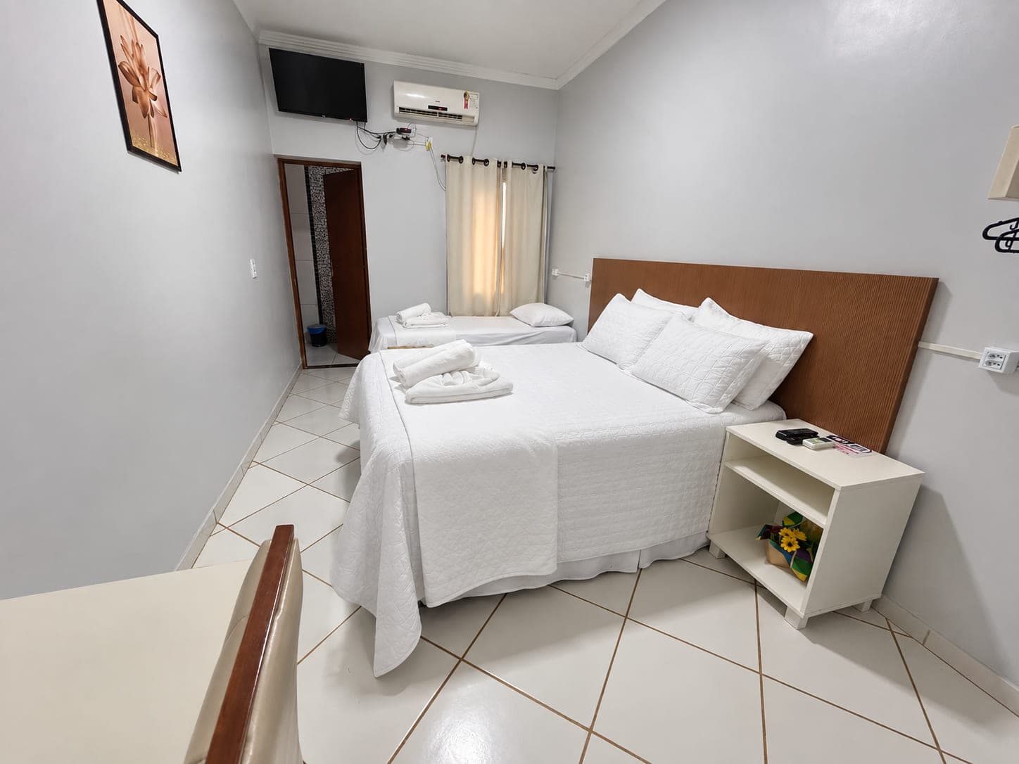 Quarto do Garden Hotel com cama de casal e cama de solteiro, ar-condicionado e TV